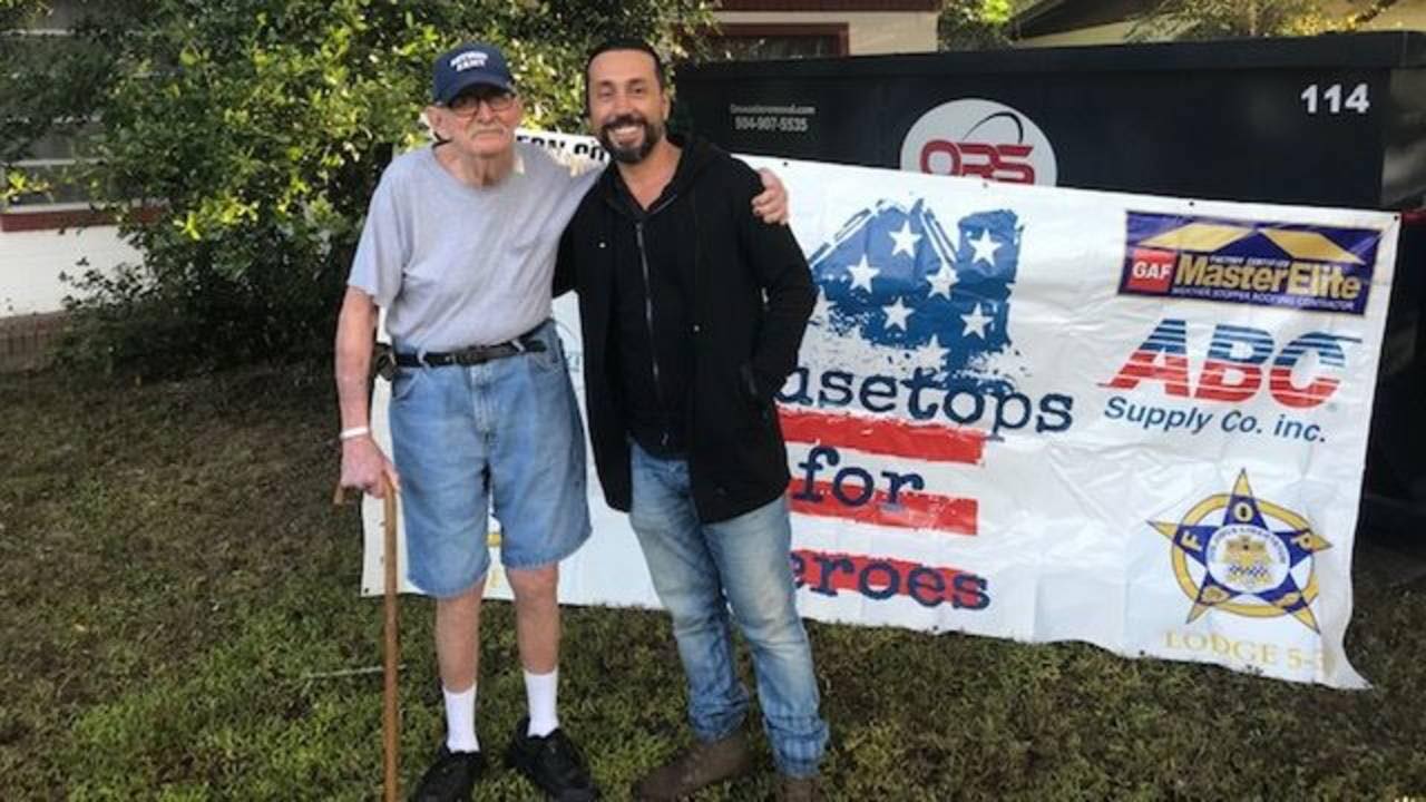 Southern Coast Roofing presenting at a Rooftops for Heroes event with sponsor banners